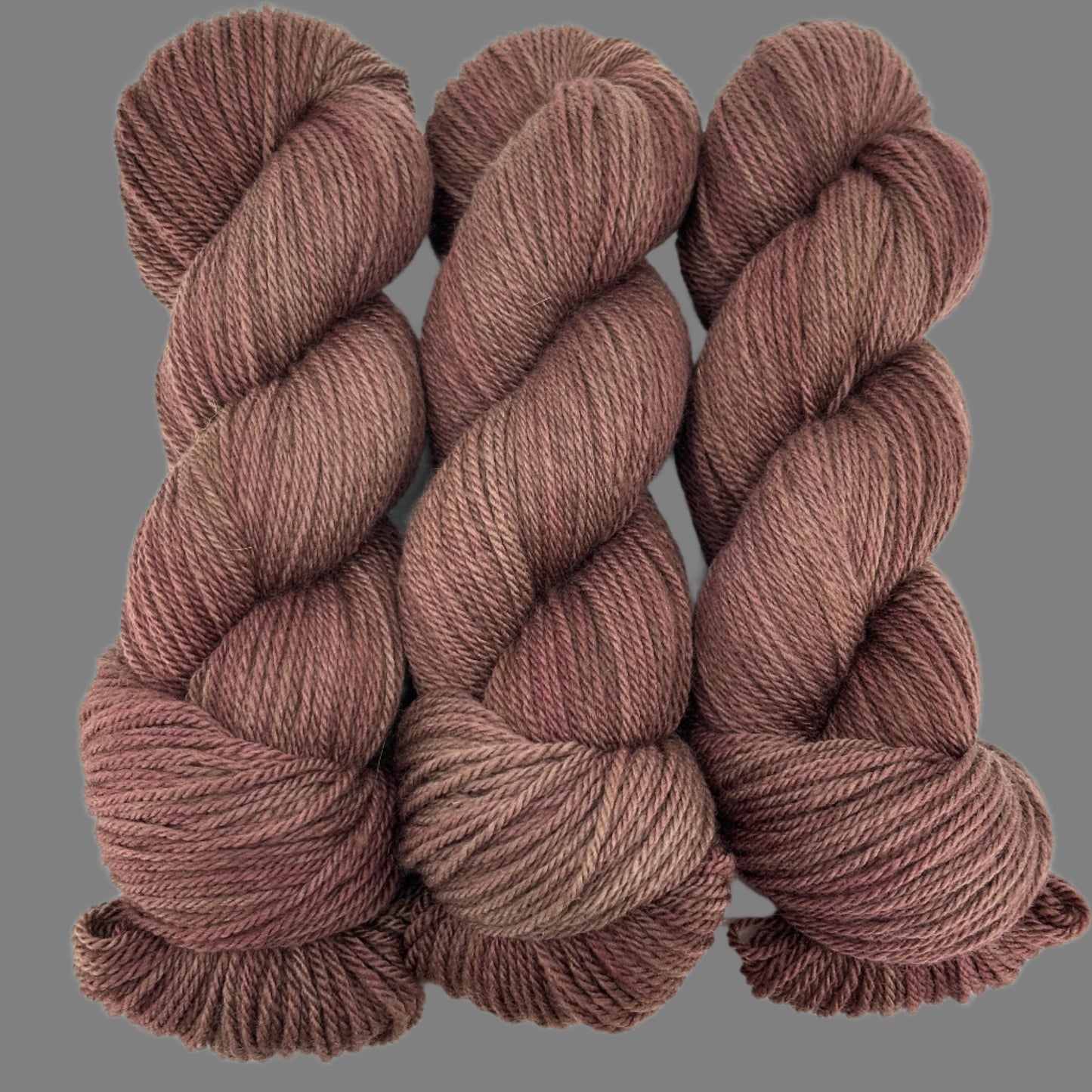 Three skeins of brown yarn on a light gray background