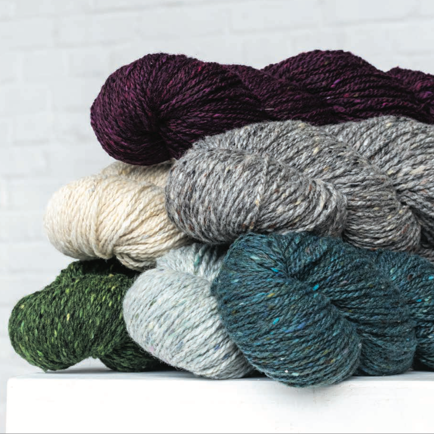 Stack of yarn skeins in various colors on a light background