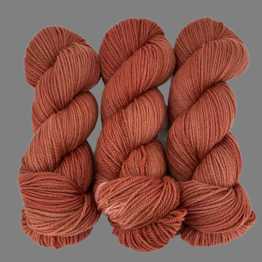 Three skeins of rusty red brown yarn on a gray  background