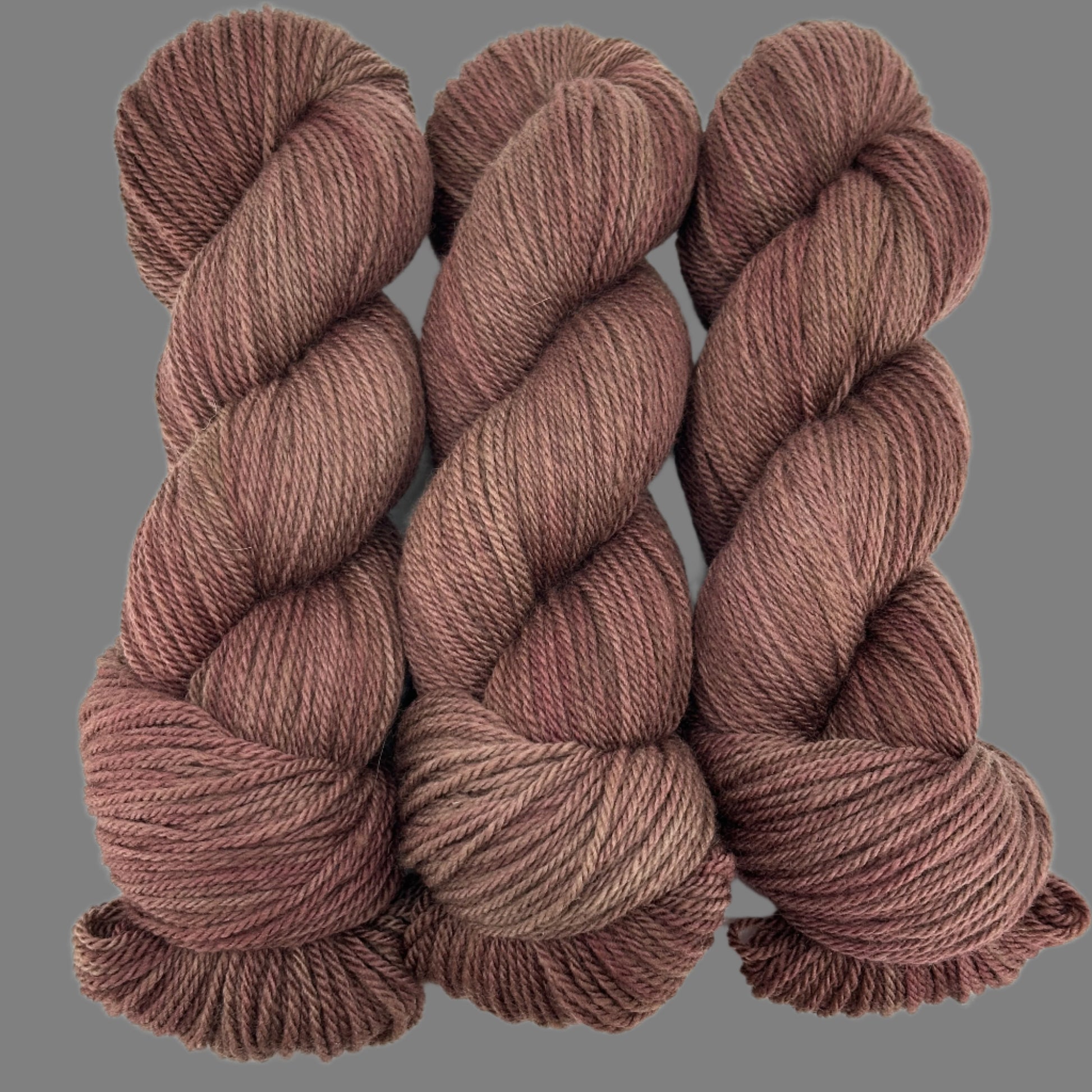 Three skeins of brown yarn on a light gray  background