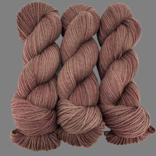 Three skeins of brown yarn on a light gray  background